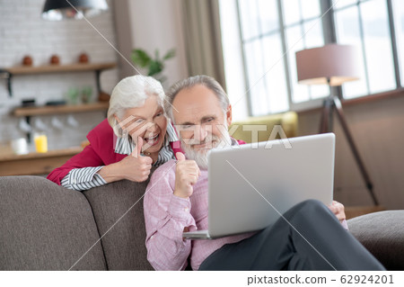 Elderly married couple looking joyful while having video call 62924201