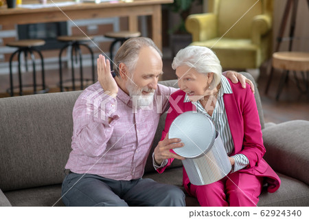 Grey-haired elderly lady opening gift box and smiling 62924340