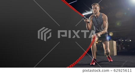 Young healthy man athlete doing exercise in the gym with ropes, flyer with copyspace Young healthy man athlete doing exercise in the gym with ropes, flyer with copyspace 62925611