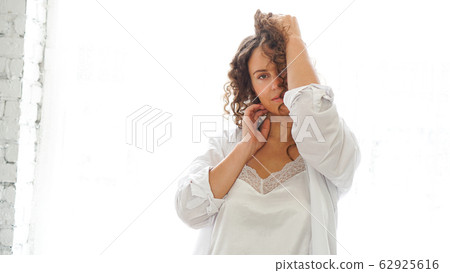 Sexy young woman in white shirt in bedroom - white light from window Sexy young woman in white shirt in bedroom - white light from window 62925616