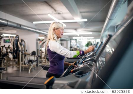 A senior woman in gym doing cardio work out exercise. A senior woman in gym doing cardio work out exercise. 62925828