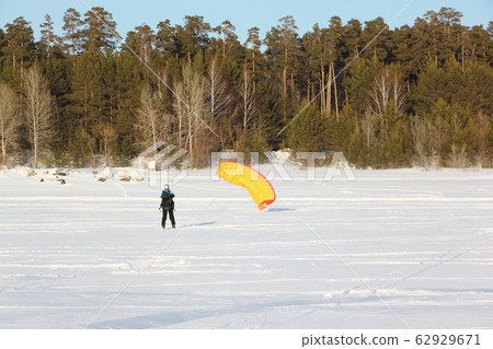 Man is engaged in snowkiting on the snowy surface Man is engaged in snowkiting on the snowy surface 62929671