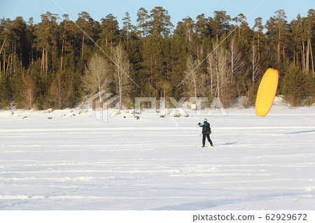 Man is engaged in snowkiting on the snowy surface 62929672