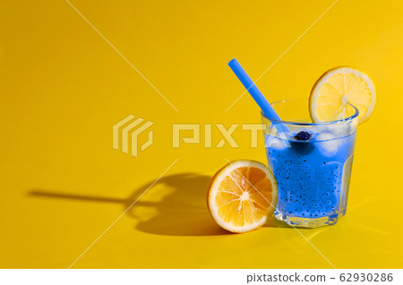 Blue cocktail with chia on yellow background. Blue cocktail with chia on yellow background. 62930286