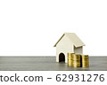 A small wooden house model with stack of coins. 62931276