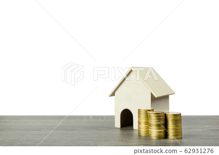 A small wooden house model with stack of coins. 62931276