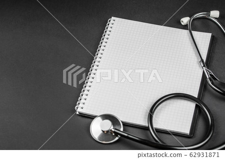 stethoscope with empty notebook on dark background stethoscope with empty notebook on dark background 62931871