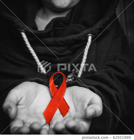 child with AID red ribbon on a dark background 62931999