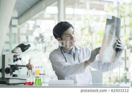 Doctor checking examining chest x-ray film of patient at ward hospital.  62933212