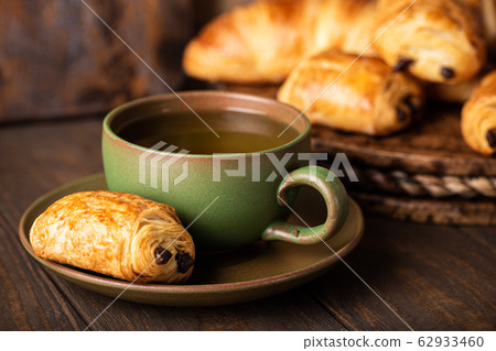 Green cup of tea with mini chocolate bun Green cup of tea with mini chocolate bun 62933460