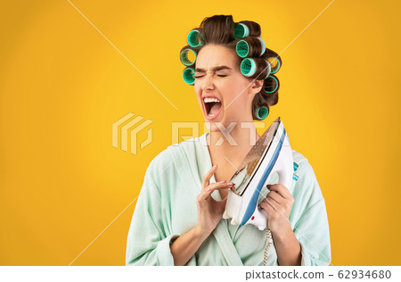 Housewife Touching Hot Iron Shouting From Pain Over Yellow Background Housewife Touching Hot Iron Shouting From Pain Over Yellow Background 62934680