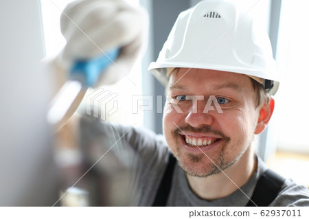 Young repairman in helmet, gloves and special uniform repairing house details 62937011