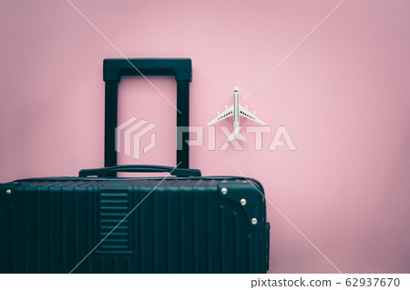 Black luggage and white airplane model on pink background Black luggage and white airplane model on pink background 62937670