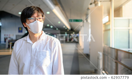 Asian man wearing mask at skytrain station Asian man wearing mask at skytrain station 62937779
