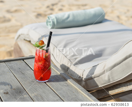 Glass of fruit juice on a beach table Glass of fruit juice on a beach table 62938613