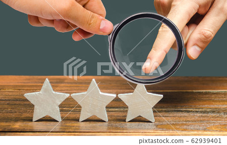 Critic points to third star. The concept of the rating of hotels and restaurants. The evaluation of visitors. Quality level, good service. Customer rating. Feedback. Critic points to third star. The concept of the rating of hotels and restaurants. The evaluation of visitors. Quality level, good service. Customer rating. Feedback. 62939401