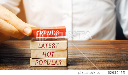 Businessman puts wooden blocks with the words Trends, latest, hot, popular. Popular and relevant topics. New ideological trends. Recent and latest trend. Evaluation methods. 62939435