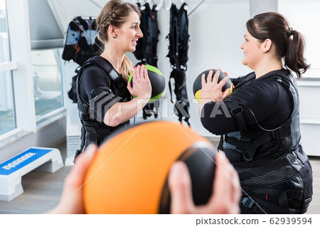 Skinny and big woman having ems training with medicine ball Skinny and big woman having ems training with medicine ball 62939594