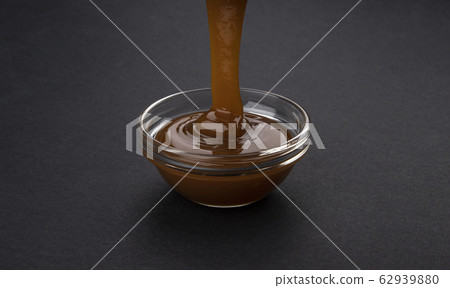 Pouring caramel sauce on black background 62939880