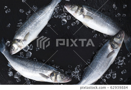 Frame made of raw seabass fish on black background, top view 62939884