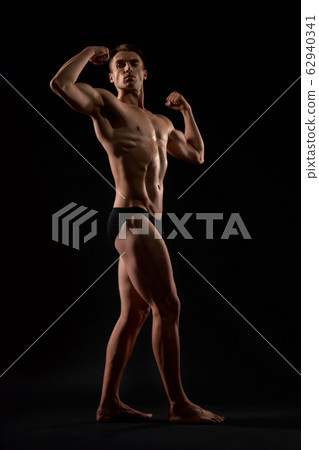 Male bodybuilder demonstrating contest pose. Male bodybuilder demonstrating contest pose. 62940341