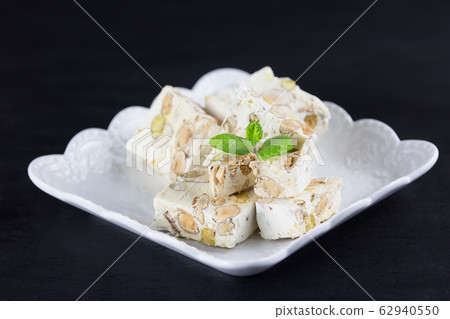 Italian torrone or nougat with almonds and pistachios from Apulia, traditional christmas sweets. Copy space 62940550