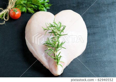 Raw uncooked heart shaped chicken breast on lettuce leaves. Healthy eating concept. Sports nutrition and proteins on black background 62940552