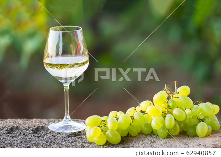 a glass of white wine and white grapes 62940857