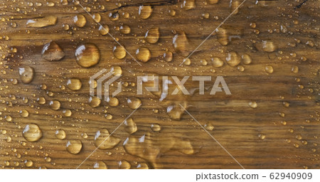 Strong wind blows away raindrops from a brown wooden surface. Classic natural combination of water and wood. 62940909