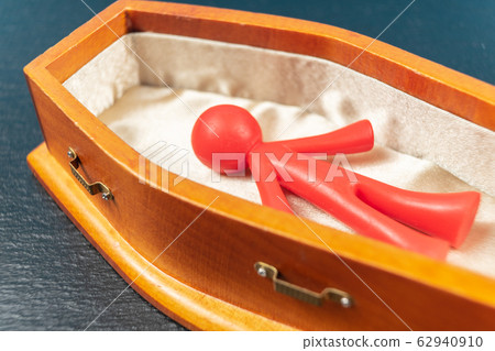COVID-19 concept. Red bright coloured figurine in coffin 62940910