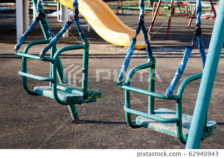 Old shabby empty swings at children playground. Old shabby empty swings at children playground. 62940943