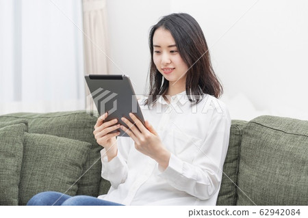A woman using a tablet in the living room A woman using a tablet in the living room 62942084