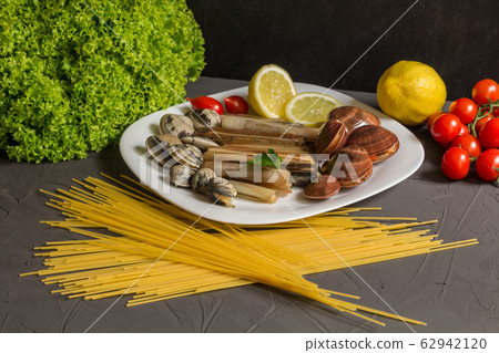 Fresh ingredients for cooking spaghetti and mussels, tomato, garlic, parsley on a gray background 62942120