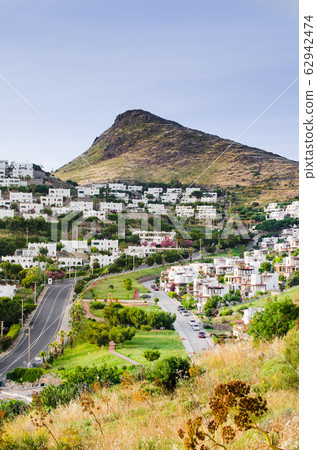 View on traditional white cubic houses, green trees, brown rocks and the road. Bodrum town, Turkey. View on traditional white cubic houses, green trees, brown rocks and the road. Bodrum town, Turkey. 62942474