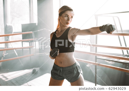 Gorgeous young woman with boxing bandage, standing in the defending position, ready to fight. . Kickboxing and fight sport concept Gorgeous young woman with boxing bandage, standing in the defending position, ready to fight. . Kickboxing and fight sport concept 62943029
