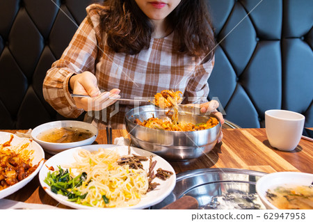 Woman eating delicious spicy bibimbap 62947958