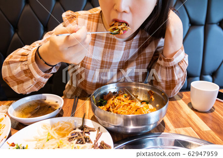 Woman eating delicious spicy bibimbap 62947959