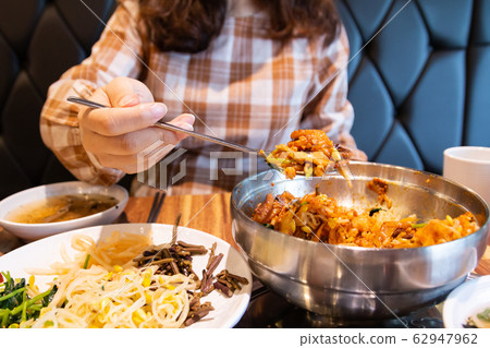 Woman eating delicious spicy bibimbap Woman eating delicious spicy bibimbap 62947962