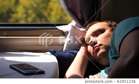 Man sleeps in train tired long journey by rail Man sleeps in train tired long journey by rail 62951236