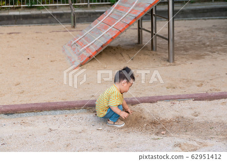男孩獨自一人在操場上玩泥土 男孩獨自一人在操場上玩泥土 62951412