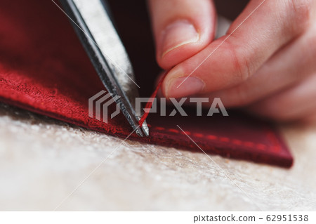 A leather craftsman works with leather. Sews A leather craftsman works with leather. Sews 62951538