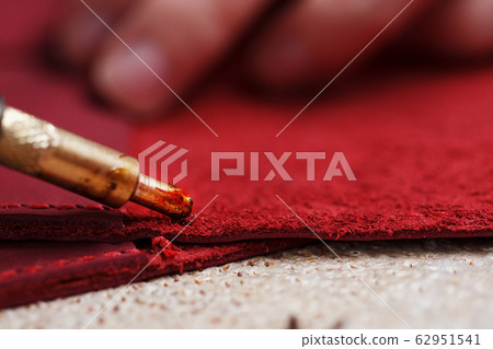 A leather craftsman works with leather. Sews A leather craftsman works with leather. Sews 62951541