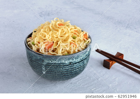 Instant noodles bowl with carrot and scallions, with chopsticks and a place for text Instant noodles bowl with carrot and scallions, with chopsticks and a place for text 62951946
