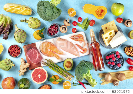 Food, top shot of many different products, with meat, fish, chicken and shrimps, vegetables and fruits, legumes, wine, pasta, cheese, and mushrooms, a flat lay on a blue background 62951975