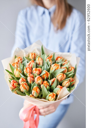 Orange color tulips in woman hand. Young beautiful woman holding a spring bouquet. Bunch of fresh cut spring flowers in female hands Orange color tulips in woman hand. Young beautiful woman holding a spring bouquet. Bunch of fresh cut spring flowers in female hands 62952600
