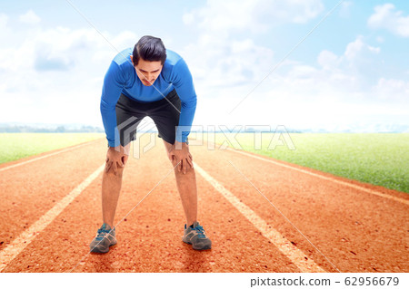 Asian runner man take a break after running on the running track  62956679