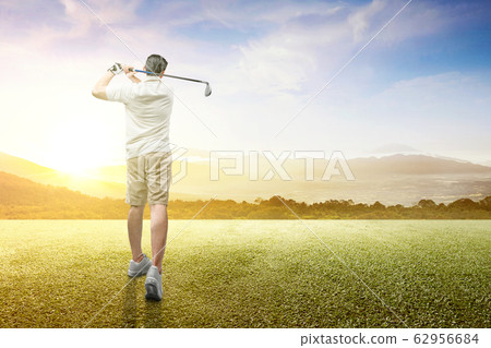 Rear view of Asian man swing the golf club and hitting the ball  62956684