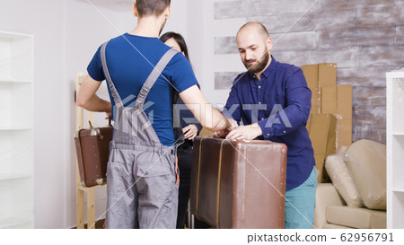 Man from delivery service arriving with suitcases of young couple 62956791