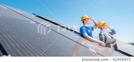 Worker and manager of solar farm looking into the sun 62956975