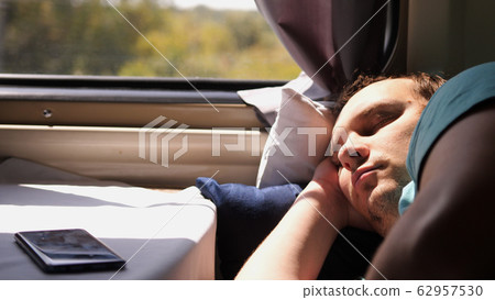 Man sleeps in train tired long journey by rail Man sleeps in train tired long journey by rail 62957530